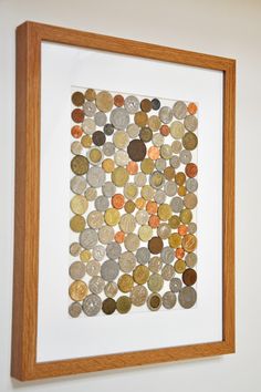 a wooden frame with coins in it hanging on the wall next to a white wall