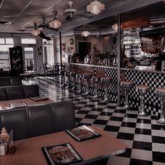 the interior of a diner with checkered flooring and green booths, black and white tile