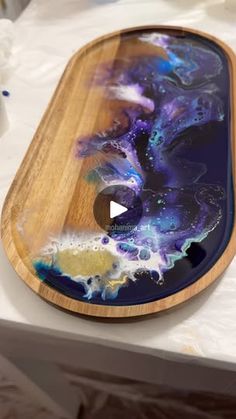 a wooden tray with an artistic painting on the bottom and sides, sitting on top of a table