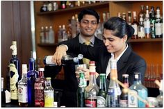 a man and woman behind a bar pouring drinks