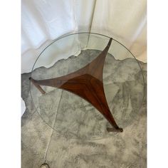 a glass and wood table sitting on top of a white cloth covered floor next to a wall