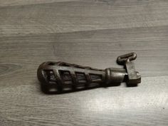 an old metal object sitting on top of a wooden floor next to a bottle opener