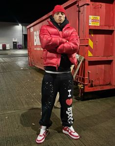 a man standing in front of a red dumpster