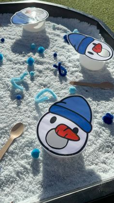 an outdoor play area with sand, spoons and snowman faces on the ground