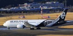 an air new zealand jet on the runway at an airport in front of some buildings