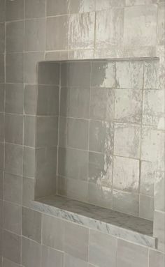 a bathroom with white tile and gray grouting on the shower wall is shown