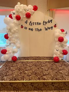 ladybug balloon arch with white and red balloons on the bed in front of it