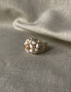 a ring with pearls on it sitting on top of a white cloth covered tablecloth