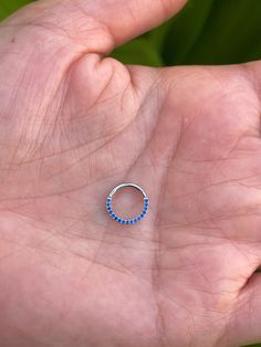 a person's hand holding a small blue beaded ring