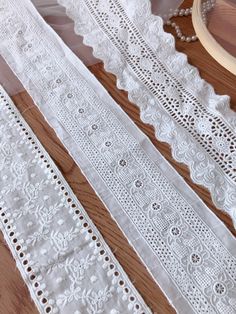 several white laces on a wooden table next to a piece of wood and some scissors