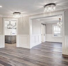 an empty living room with wood floors and chandeliers