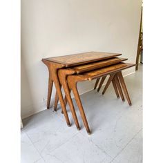 three wooden tables stacked on top of each other in a room with white tile flooring