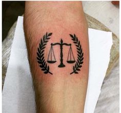 a tattoo on the leg of a person with a scale and laurel