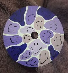 a purple and white painted circular object sitting on top of a brown fur covered floor