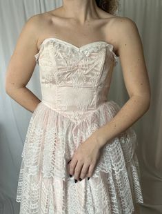 Details: maxi length; crinoline lining with blush pink and white lace, layered overlay; full, tiered skirt; dropped v-waist; strapless, sweetheart neckline; boning in bodice; zip-up closure in the back.  Damage: stain to front top layer of lace; lace appears slightly grayed in skirt overall; discoloration (dirt) to hemline).  Bust: 29 in // Waist: 25 in // Overall Length: 50 in Please note all inventory is pre-loved and sold as is. I will always do my absolute best to detail any and all damage i Pink Lace Corset Dress For Prom, Pink Corset Wedding Dress With Lined Bodice, Pink Wedding Corset Dress With Lined Bodice, Pink Corset Dress With Lined Bodice For Wedding, Pink Strapless Dress With Boned Bodice For Wedding, Pink Strapless Dress With Lined Bodice For Wedding, Pink Strapless Wedding Dress With Lined Bodice, Strapless Pink Corset Dress For Wedding, Pink Lace Corset Dress For Wedding