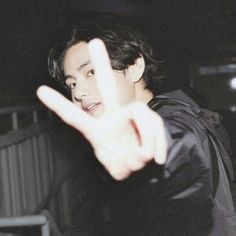 a young man making the v sign with his hand while standing in front of him