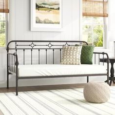 a living room with a white rug and black iron daybed in the middle of it