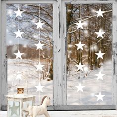 a window with white stars hanging from it's side and a small toy horse next to it