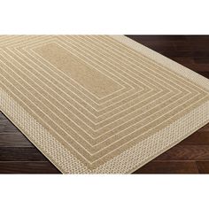 a beige area rug on top of a wooden floor