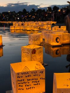 many small boxes with writing on them are floating in the water at dusk or dawn