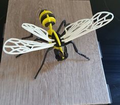 a yellow and black insect sitting on top of a wooden table