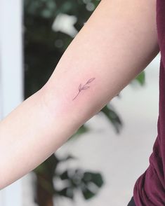 a woman's arm with a small arrow tattoo on the left side of her arm