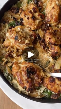 a pan filled with chicken and rice on top of a wooden table