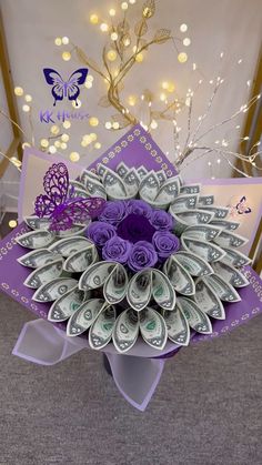 a bouquet made out of dollar bills sitting on top of a purple chair with butterflies around it