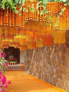 an outdoor area with flowers and plants hanging from the ceiling in front of a stone wall