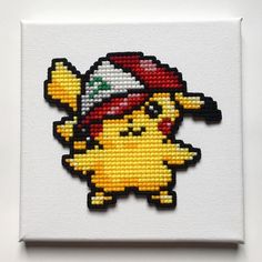 a cross stitched picture of a pikachu wearing a hat and holding a banana