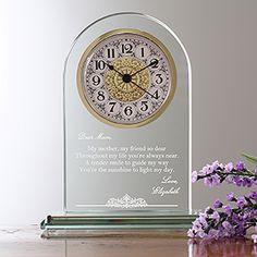 a glass clock sitting on top of a table next to purple flowers