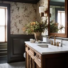 a bathroom with two sinks and a large mirror above it's countertop, along with a vase filled with flowers