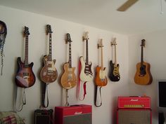 a wall with guitars and amps hanging from it's sides in front of a flat screen tv