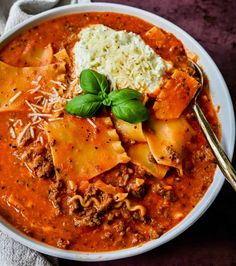 a white bowl filled with pasta and meat, topped with parmesan cheese on top