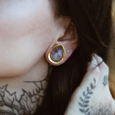 a close up of a person with tattoos on her neck and wearing earrings