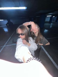 two girls are posing for the camera in an empty parking garage with their arms around each other