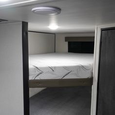 there is a small bed in the corner of this room with no sheets on it