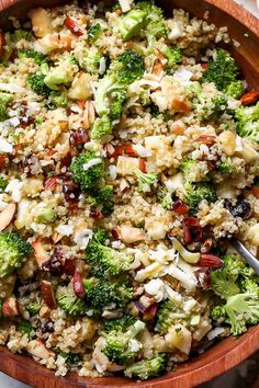 a bowl filled with broccoli, nuts and other food on top of a table