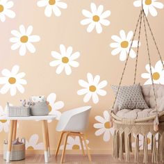 a baby's room with white and yellow daisies on the wall next to a hammock