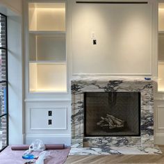 an empty living room with a fireplace and built in bookshelves