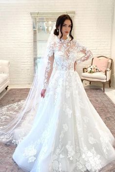 a woman in a white wedding dress standing next to a couch with a veil on her head