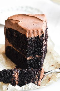 a slice of chocolate cake on top of a piece of parchment paper with a fork