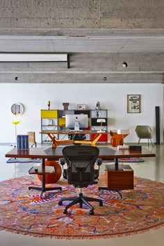 an office area with a rug, chair and desk in the middle of the room