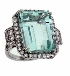 an aqua green and white topazte ring with diamonds on the sides, set in 18k white gold