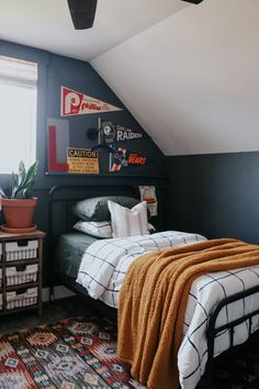 a bedroom with black walls, white bedding and an orange blanket on the bed