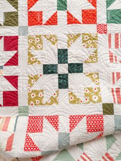 a close up of a quilt with many different designs on it, including red and green