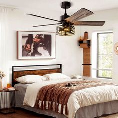 a bed room with a neatly made bed and a fan hanging from the ceiling above it