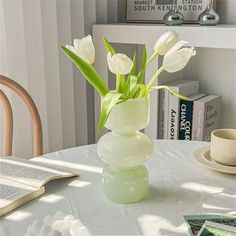 there is a vase with white flowers in it on the table next to some books