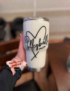 a person holding up a cup with the word volleyball on it and a sticker in their hand