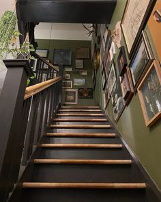 there are pictures on the wall above the stairs and below the bannister railing